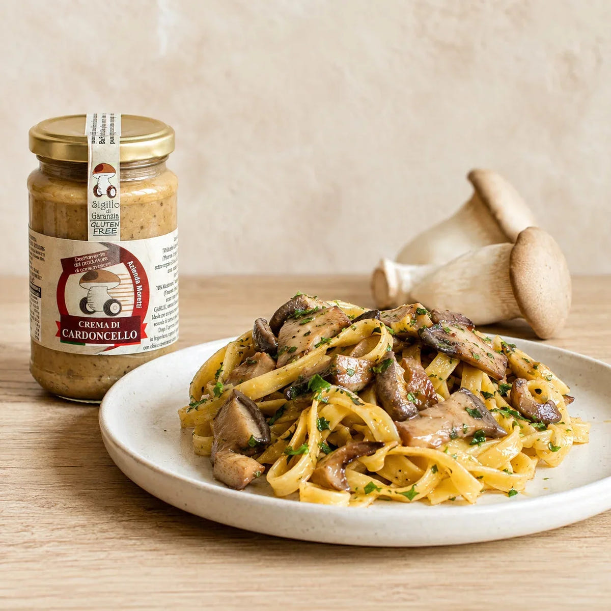 Vasetto di crema di cardoncello Moretti accanto a un piatto di pasta con funghi.